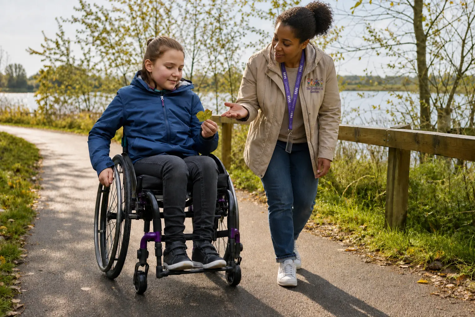 A branded Children of Goshen practitioner supporting a wheelchair user during outdoor learning